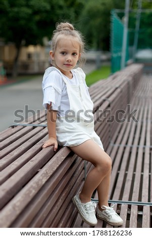 A little girl in light clothes walks in the park. Walk outdoors.summer day.
