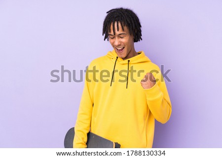 Young african american man isolated on purple background with a skate