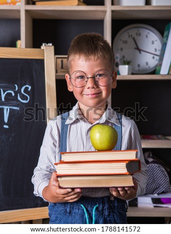 Portrait of cute little boy holding book in classroom. Happy International Literacy Day. Royalty-Free Stock Photo #1788141572