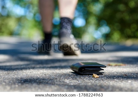 Photo of the sidewalk and legs of a man who lost a black leather wallet while walking