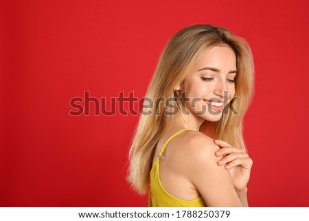 Beautiful young woman with blonde hair on red background. Space for text