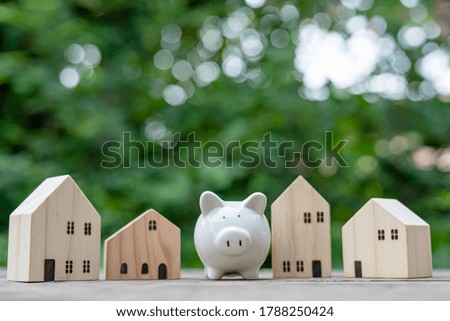 Piggy bank and a wooden house around It means saving money to buy the best home. And the bright green bokeh background Concept saving money, growth, economic business and investment.