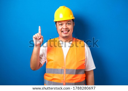 Asian workers wearing safety vest and helmets are seen looking for ideas in completing work against blue background