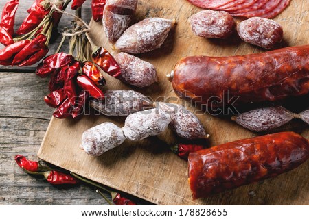 Top view on set of salami sausages served with red hot chili peppers on wooden cutting board. See series. Royalty-Free Stock Photo #178828655