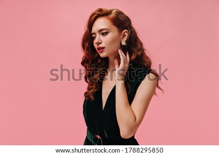 Portrait of curly woman in velvet dress on pink background. Wonderful lady with ginger wavy hair in dark green outfit posing.. Royalty-Free Stock Photo #1788295850