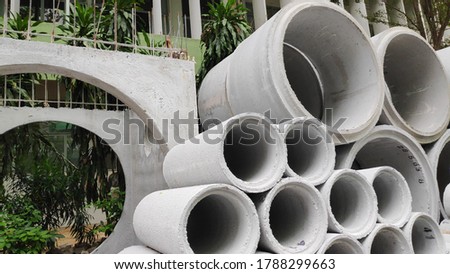 Concrete drainage pipes are stacked for construction.