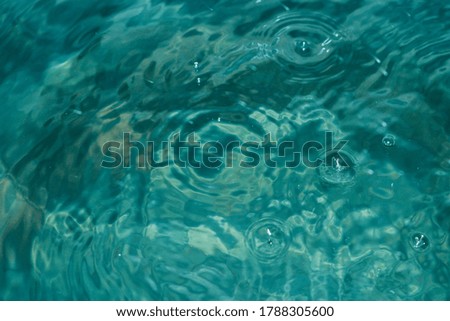 The emerald-blue water surface with water waves and bubbles is perfect for design.