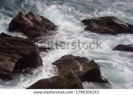 Picture of waves hitting rocks at the shoreline of a beach.