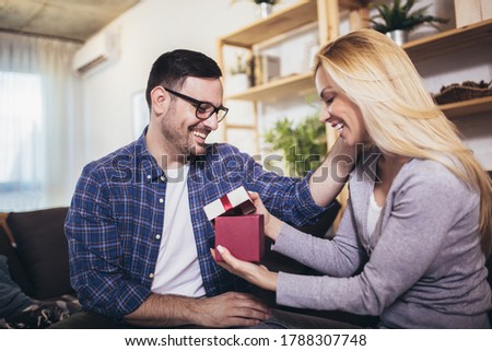 Happy couple with gift box at home celebrate Valentine's Day.