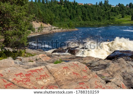 Downstream Namforsen water power plant and  petroglyph on the cliff in foreground, picture from the Northern Sweden.