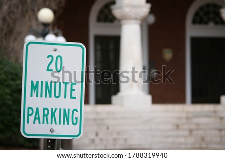 Green and white 20 Minute Parking Sign in front of a Building