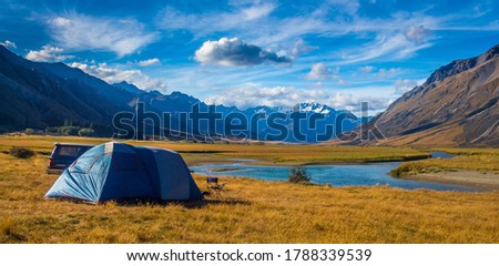 A tent pitched beside the Ahuriri River, surrounded by mountains, in Cantebury, South Island, New Zealand Royalty-Free Stock Photo #1788339539