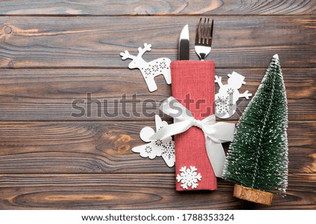 Top view of fork and knife tied up with ribbon on napkin on wooden background. Christmas decorations and New Year tree. Happy holiday concept with empty space for your design.