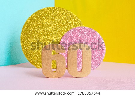 golden number "60" on a multicolored blue-yellow-pink background and two shiny gold and pink circles. happy birthday greeting card concept.
