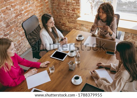 Young caucasian business woman in modern office with team. Creative meeting, tasks giving. Women in front-office working. Concept of finance, business, girl power, inclusion, diversity. Top view.