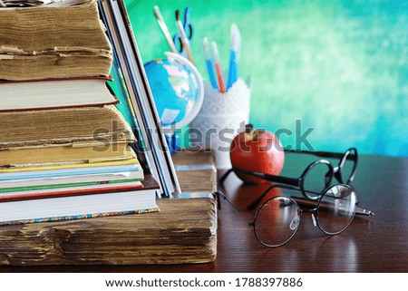 Education concept. A stack of textbooks and a book on the desk with glasses and computer. School breakfast apple and homework.