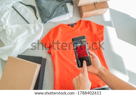 Selling online by taking photo of clothes with phone app and doing e-commerce business woman at home with shipping boxes. Royalty-Free Stock Photo #1788402611