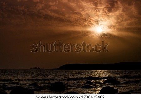 orange sunset on the beach with mountains in the background