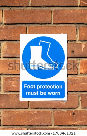 a sign on a brick wall stating that foot protection must be worn