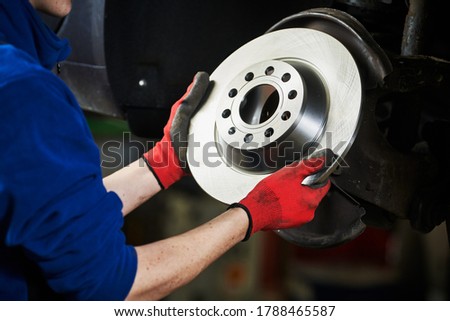 Automobile brake disk replacement in car repair shop or garage