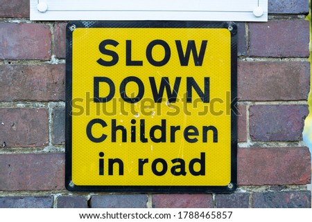 a yellow sign on a brick wall outside a school stating slow down children in road
