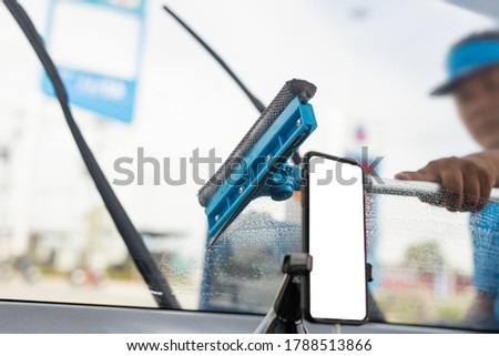 Employee using sponge to clean a car windscreen at gas station