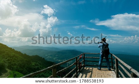 Tourists who stand to take pictures on the bridge to see the view with beautiful mountains and skies with a rear view.