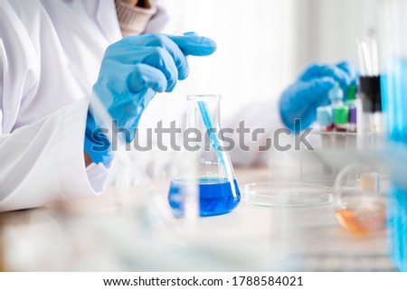 Medical scientists released a sample pipetted into a test flask to analyze the virus in a chemical laboratory. Scientific research concepts.