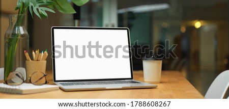 Cropped shot of worktable with blank screen laptop and office supplies in glass partition office room, clipping path.