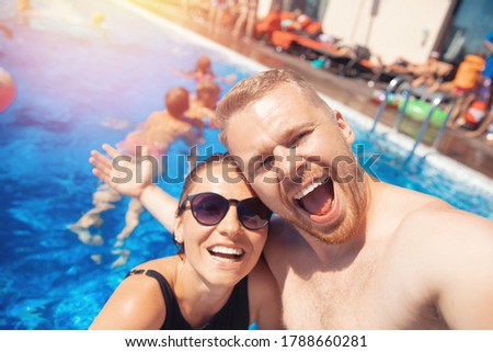 Happy loving couple Caucasian man and woman hugging and making selfie photo on background of pool. Smile and tanned skin summer time.