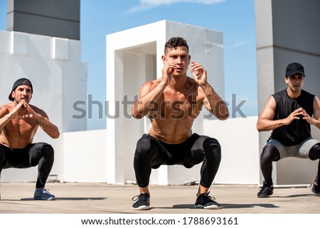 Group of fit sports men doing squat bodyweight workout training outdoors on building rooftop in sunlight - exercise in the open air concept Royalty-Free Stock Photo #1788693161