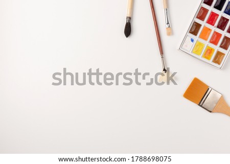 Watercolor paints, brushes isolated on white background. Copy space. Top view. Flat lay.