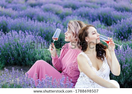 two women drink wine in a lavender field
