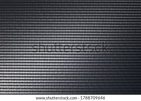 carbon fibre or graphite sheet with background texture beam of light and color gradient in close up full frame