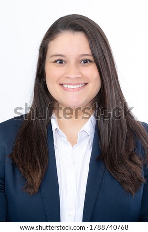 Frontal studio portrait of a business young woman. She is wearing a blue navy suit and a white shirt. She is smiling to the camera.