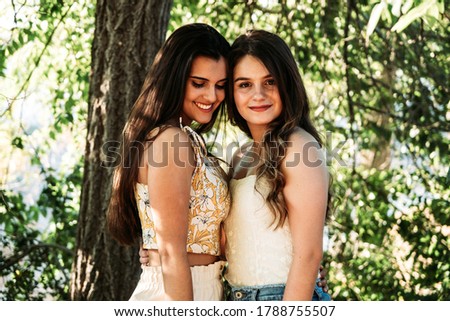 two young women friends in the forest with trees in the background