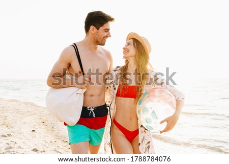 Romantic young couple walking together at the sunny beach