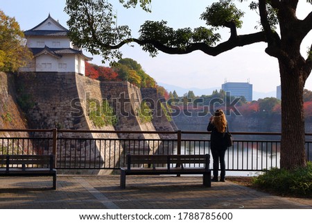 Tourist taking photos of Japanese landmark. Osaka Castle moat and Castle Park, Japan.