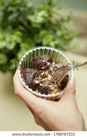 Brown sweets with walnut in hand holding a fork with green background