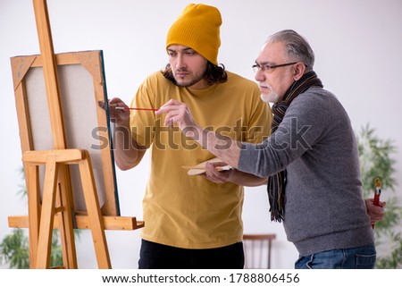 Old man taking lesson from young painter