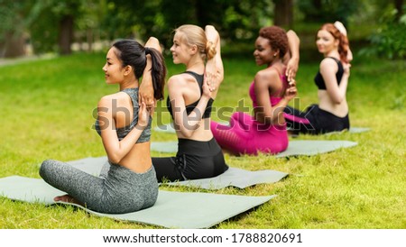 Group of multiracial girls attending outdoor yoga practice at city park, blank space. Panorama