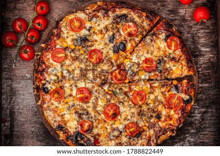 fresh rustic homemade italian style pizza with tomato olives cheese and salami in wooden dark vintage background