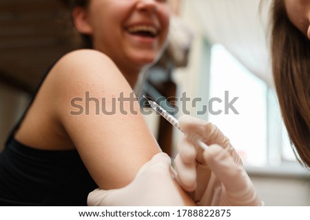Girl smiling while vaccinating in the shoulder. Immunisation by professional health worker, focus on shoulder Royalty-Free Stock Photo #1788822875