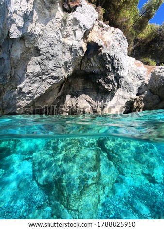 Underwater split line photo of beautiful caves with deep turquoise sea and Pine trees of Kastani beach well known for Mamma Mia movie filming, Skopelos island, Sporades, Greece
