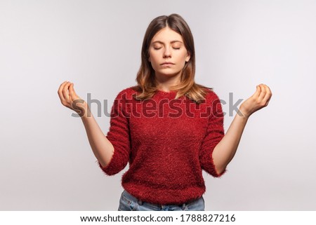 Zen, inner peace. Portrait of calm girl in shaggy sweater concentrating her mind, keeping hands up in mudra gesture, meditating, yoga exercise breath technique reduce stress. studio shot isolated