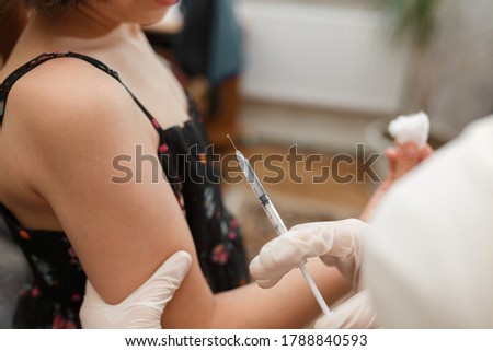 Young girl receiving vaccination immunisation by professional health worker, focus on shoulder. Medical syringe with vaccine. Health care and medicine concept. Royalty-Free Stock Photo #1788840593