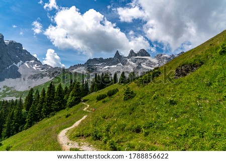 the three towers in the mountains from Vorarlberg. the mountains are in the clouds, shined by the sun. changing light conditions in the Alps. Alps of Austria. between Austria and Switzerland. Royalty-Free Stock Photo #1788856622