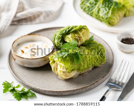 Savoy cabbage rolls stuffed with meat rice and herbs served with sour cream and green parsley leaves. Vegetable supper, dinner or appetizer. Food on plate.Close up view. White wooden table background. Royalty-Free Stock Photo #1788859115