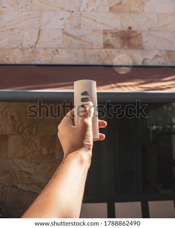 hand with a remote control lowering or raising an awning