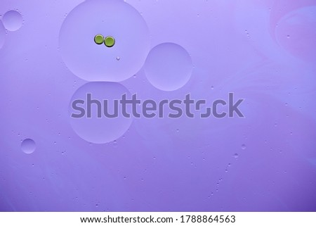 Current collection of brilliant backgrounds for your design. Close-up shot of green oil bubbles and water circles on violet surface with swirls.